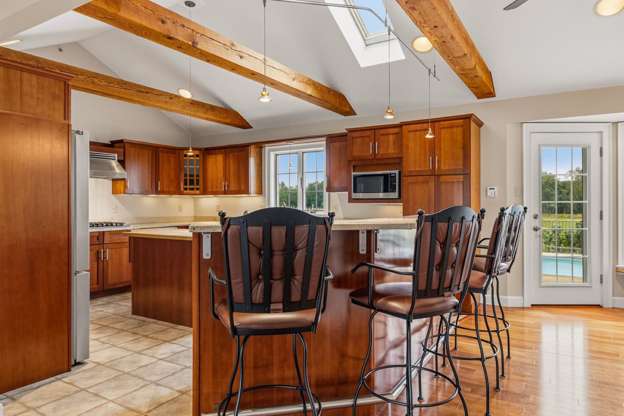 The kitchen island with stools under the beams and the skylight