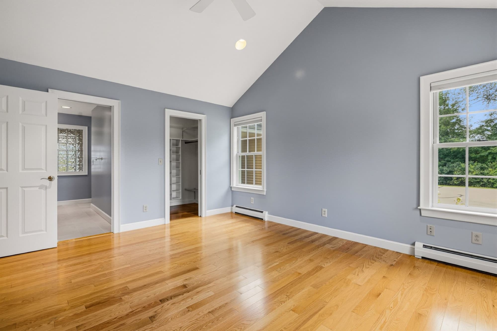 The primary bedroom with a cathedral ceiling and doors to the bath and the walk-in closet