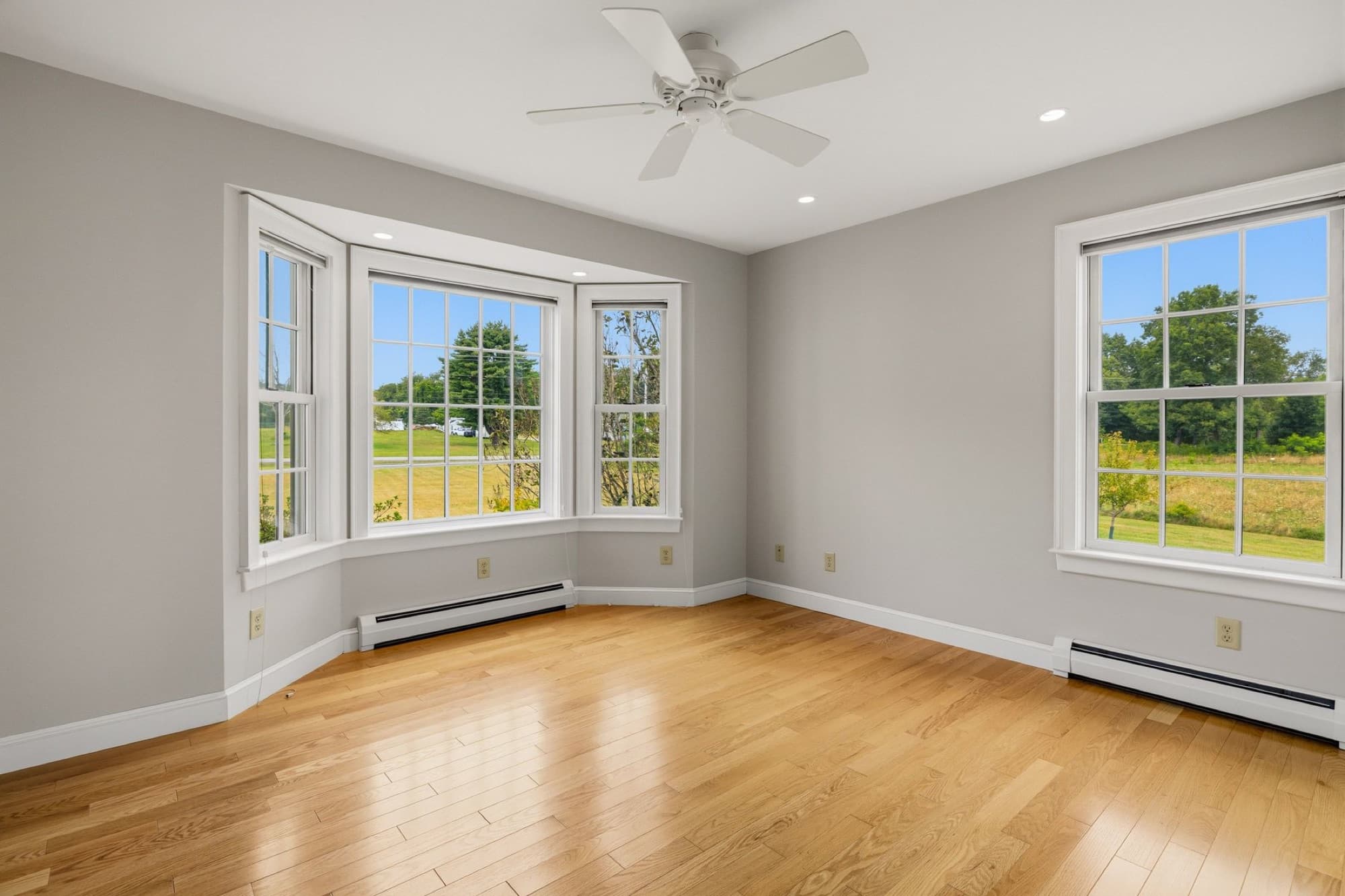 A bedroom with a bay window and a ceiling fan