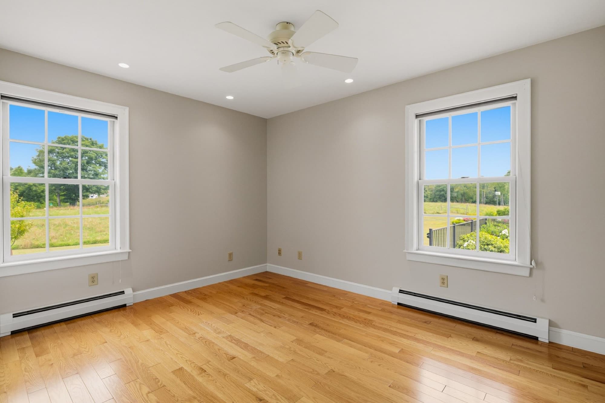 A bedroom with 2 windows over the fields
