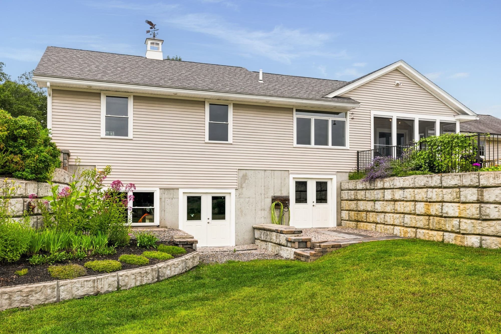 The back of the house from the lawn, with the walkout basement doors and the stone retaining walls